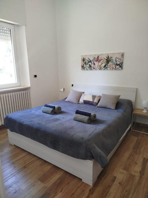 een witte slaapkamer met een groot bed met blauwe lakens bij Bilocale Home Project 2 in Novara