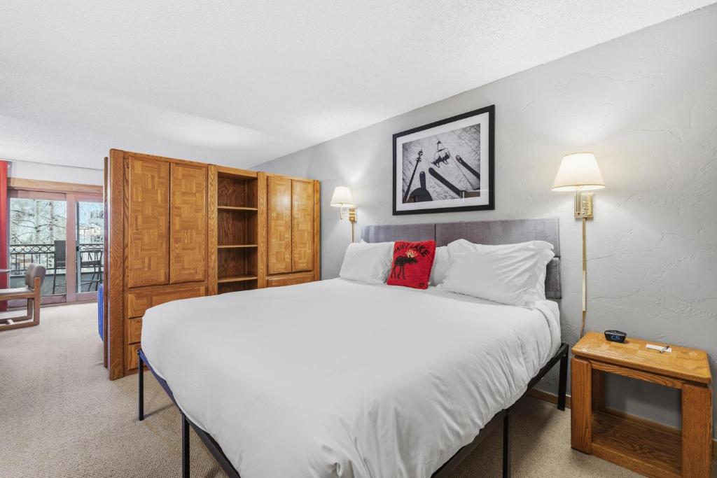 a bedroom with a white bed and a wooden cabinet at Lift House Lodge, Pet Friendly Studio Condo in Vail