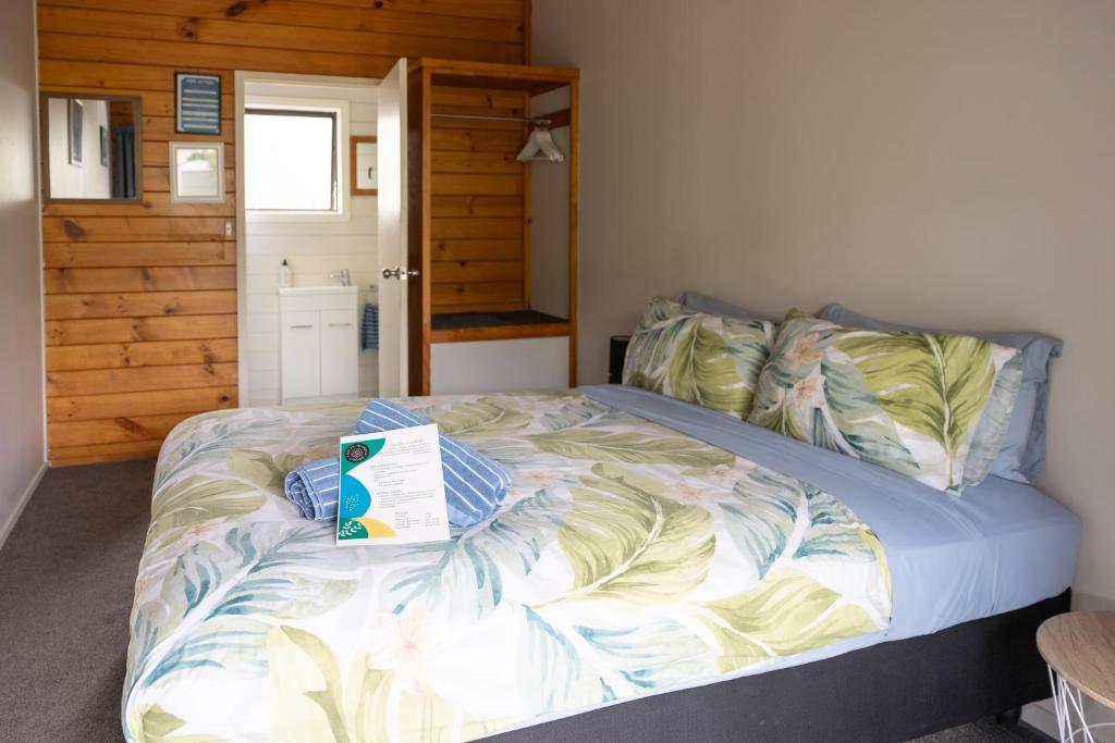 a bedroom with a bed with a book on it at Bay of Islands Lodge in Paihia