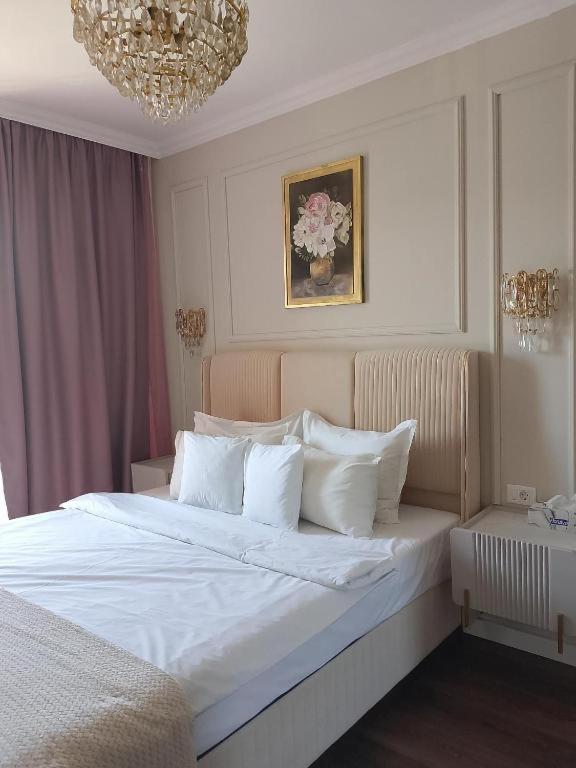 a bedroom with a large white bed with a chandelier at Apartament Green Tara in Oradea