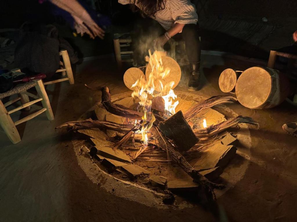 une personne debout au-dessus d'un foyer avec des bûches dans l'établissement Travel Oasis Merzouga Camp, à Merzouga