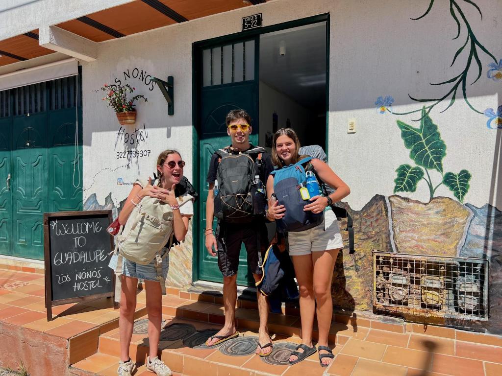 een groep van drie mensen die buiten een huis staan bij Los Nonos Hostel in Guadalupe