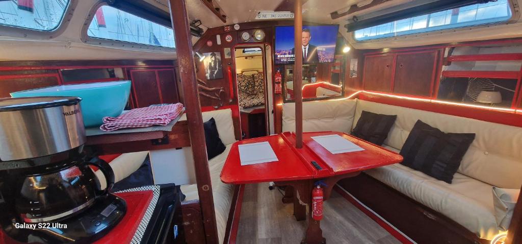 een kleine kamer met een rode tafel en een bank bij Voilier de tout confort in Cherbourg en Cotentin