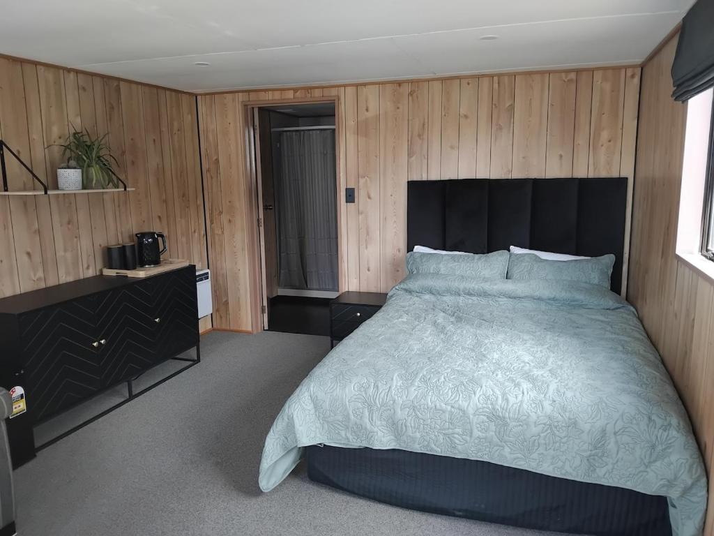 een slaapkamer met een groot bed en houten wanden bij TuiStay in Cromwell