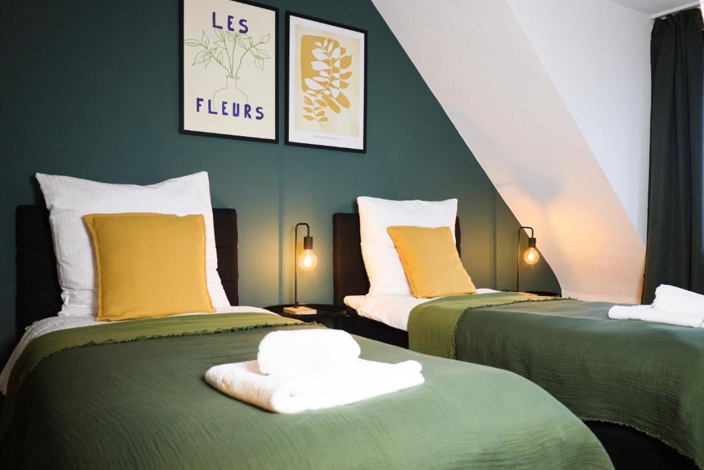 two beds with green and yellow pillows in a room at Nalia Homes - Elegant Central Apartment in Pinneberg