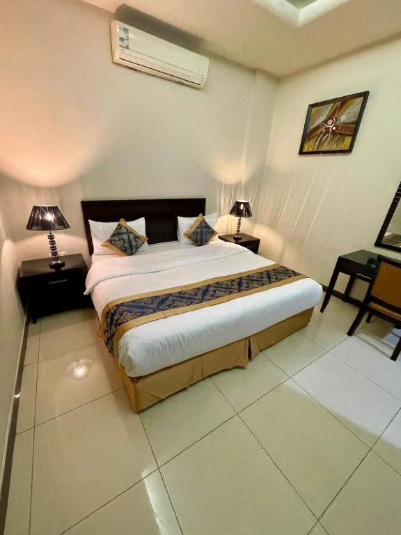 a bedroom with a large bed with two lamps on it at Quiet Rooms 8 Serviced Apartments in Riyadh
