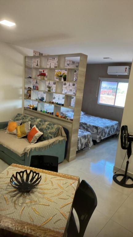a living room with two beds and a table at Flat Getsêmani Olímpia a 10min do Thermas dos Laranjais in Olímpia