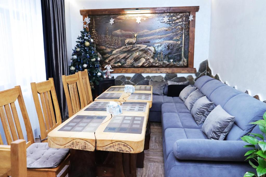 een woonkamer met een blauwe bank en een kerstboom bij Садиба "Hutsulyana" in Dobrovelychkivka