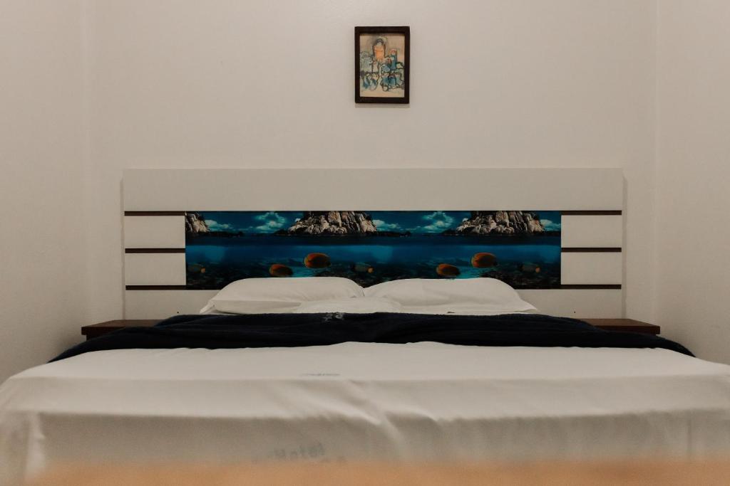 een slaapkamer met een wit bed met een schilderij aan de muur bij Hotel A BARCA in Bom Jesus da Lapa
