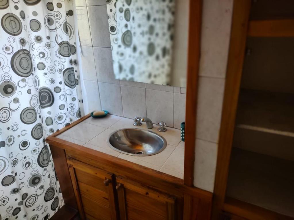 a bathroom sink with a mirror and a shower curtain at Amistad in Villa Gesell