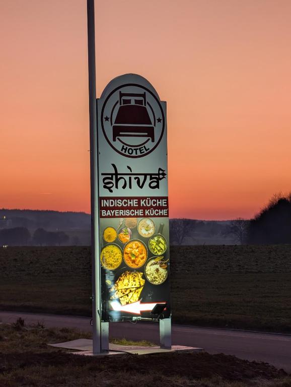 un cartello sul ciglio di una strada con del cibo di Hotel Shiva a Maingründel
