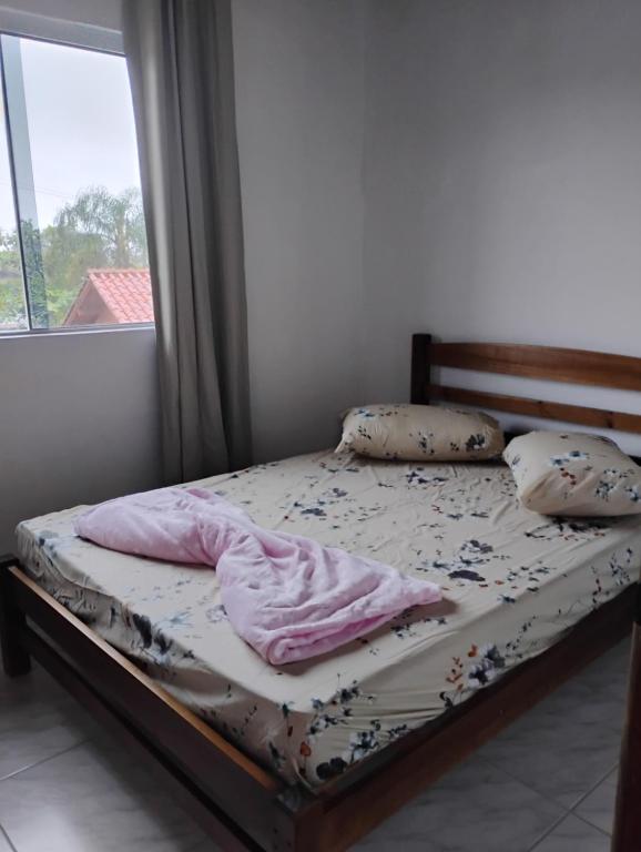 a bed sitting in a bedroom with a window at Aconchego Maria Laura in Palhoça