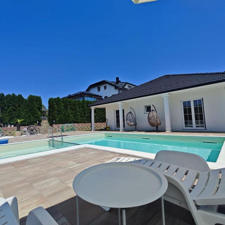 a pool with a table and chairs next to a house at Villa Leah in Bihać