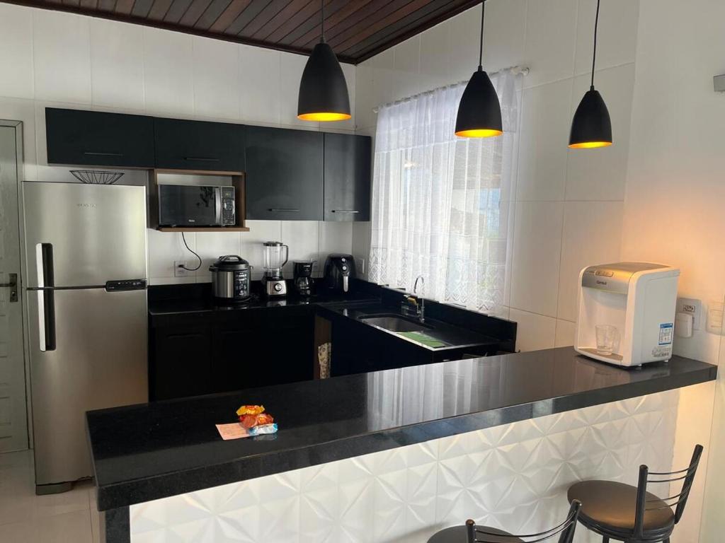 a kitchen with a black counter top and a refrigerator at Casa de Temporada, 2 Quartos com Ar - Prado BA in Prado