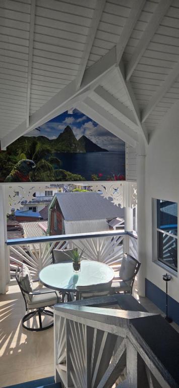 een patio met een tafel en stoelen en een muurschildering bij Martha's House Audi in Soufrière
