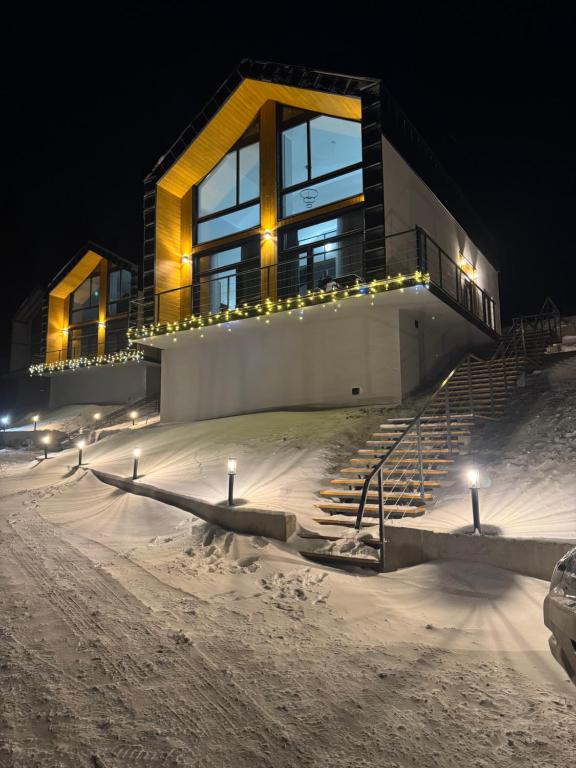 a house in the snow at night with lights at cottages GRUN in Yablunytsya