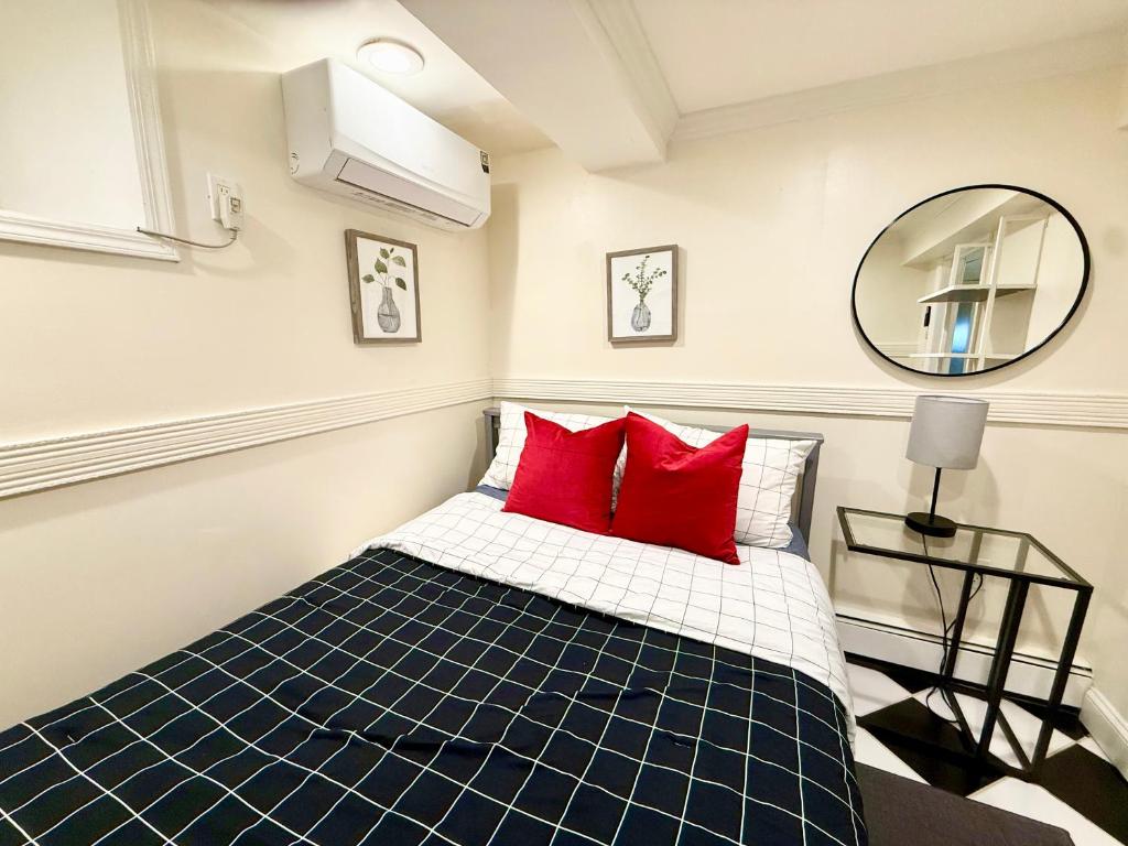 ein Schlafzimmer mit einem Bett mit roten Kissen und einem Spiegel in der Unterkunft 5-A Diamond in Yonkers in Yonkers