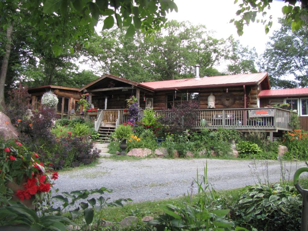 a log cabin with a porch and flowers at Shambhala Bed and Breakfast in Buckhorn