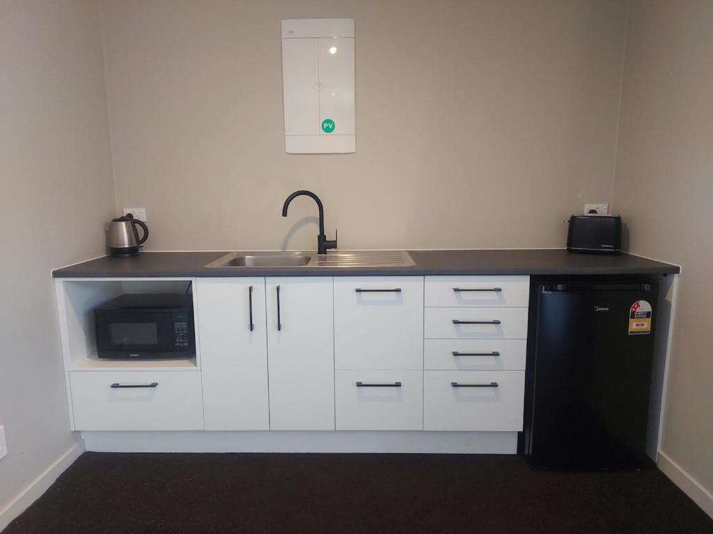 a kitchen with a sink and a black refrigerator at Mapua Hills Hideaway in Upper Moutere