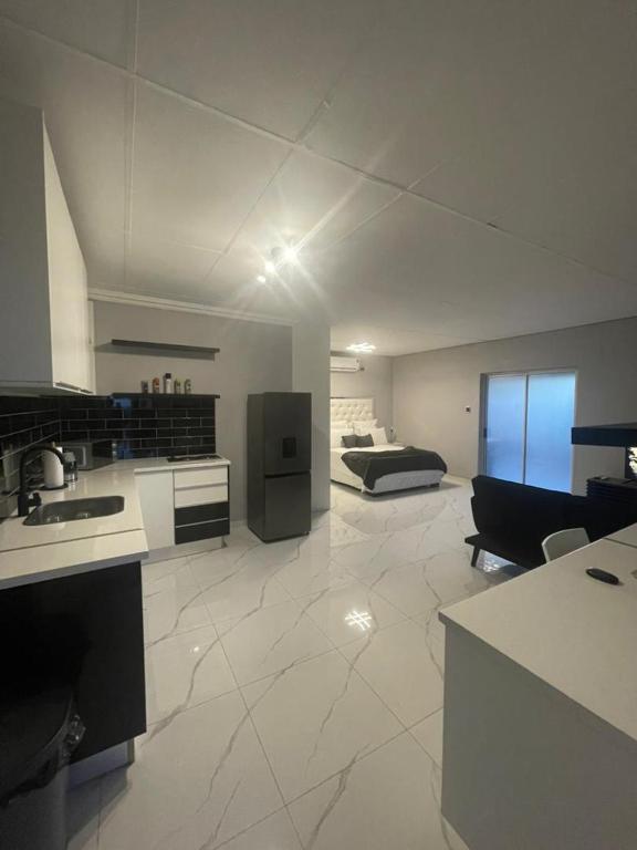a kitchen and living room with a bed in the background at Pine Self-Catering Unit in Windhoek