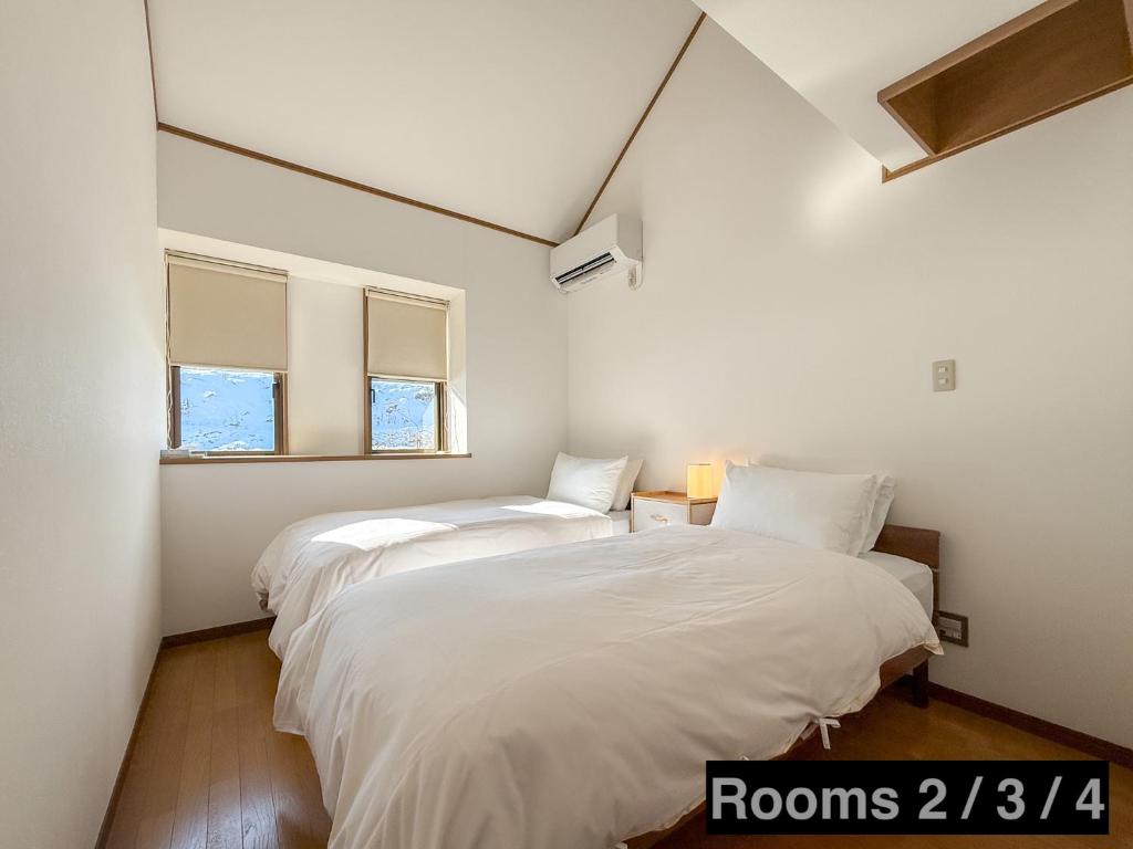 two beds in a room with two windows at KijimaBase - Base 1 in Kijimadaira