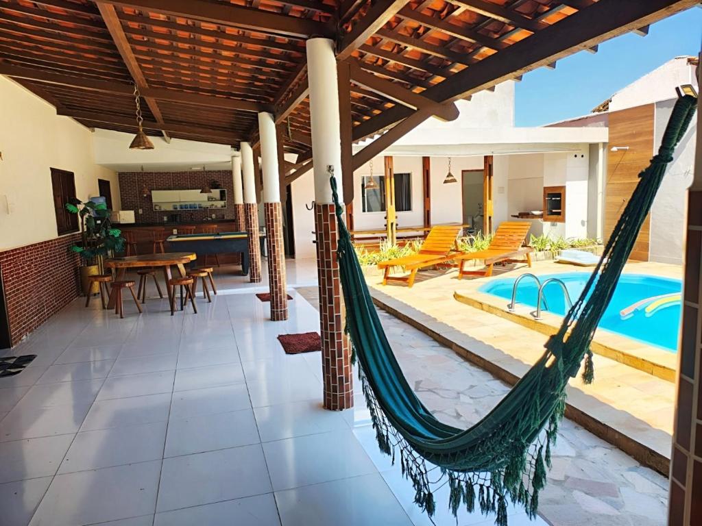 an outdoor patio with a hammock and a swimming pool at Casa confortável c piscina, lazer e espaço gourmet in Barra de São Miguel