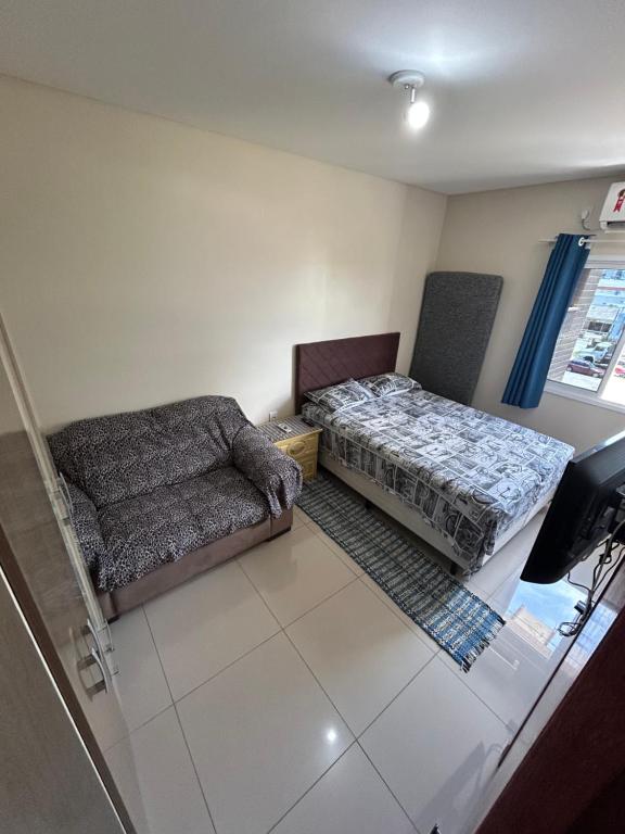 a living room with a bed and a couch at Edificio Freitas in Imbituba