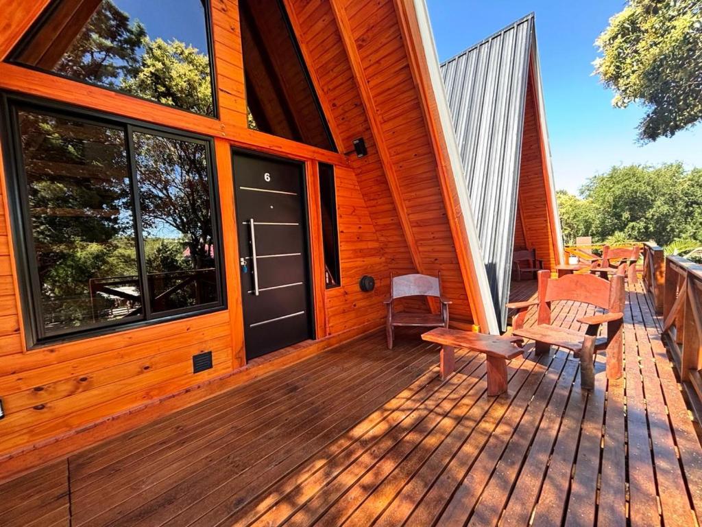 een veranda aan de voorzijde van een houten huis met een bank bij A Mi Manera Apart in Merlo