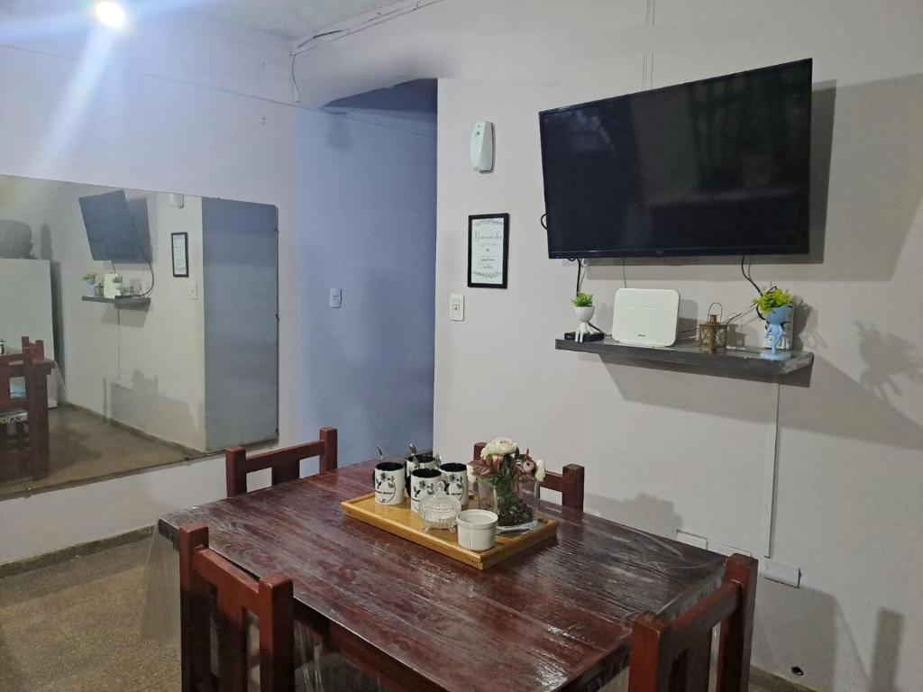 een houten tafel met stoelen en een televisie aan de muur bij Alojamiento Marlugm in Corrientes