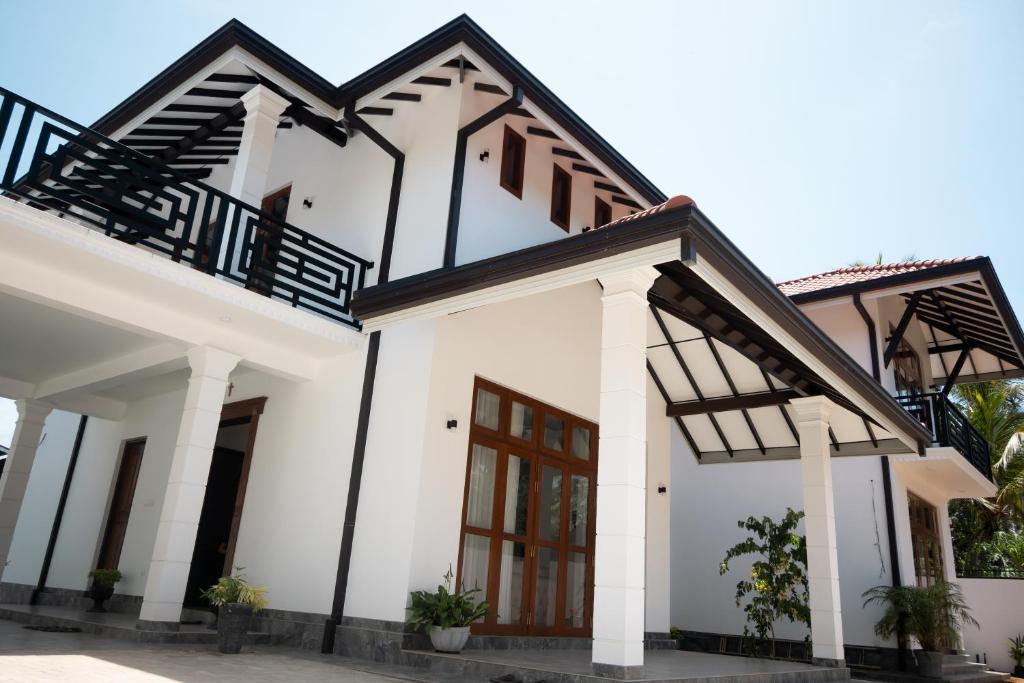 a house with white walls and wooden doors at Ashasha Villa in Negombo