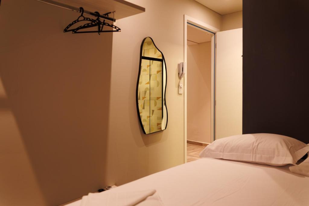 una camera da letto con un letto e uno specchio sul muro di Lou Suites - 15 - Cantinho Charmoso a Guarapuava