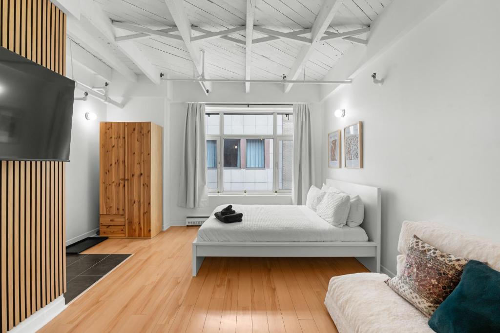 a living room with a bed and a tv at Métropolitain Le Cachet in Quebec City