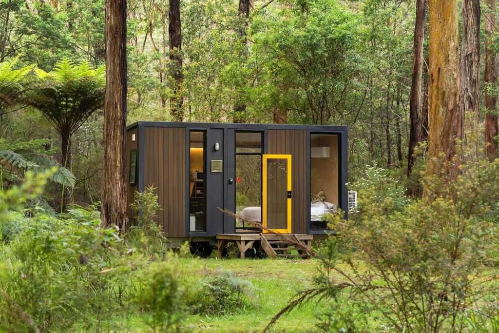 a tiny house in the woods with a yellow door at Quantum Field by Tiny Away in Toolangi