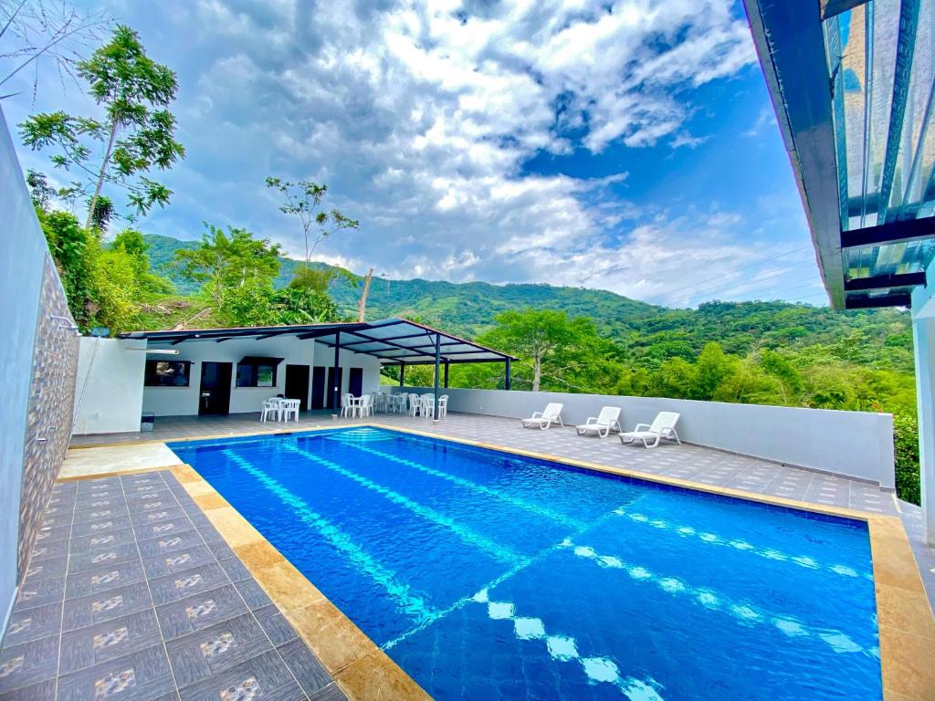 a swimming pool with chairs and a building at Finca Tres Potrillos Villeta in Villeta