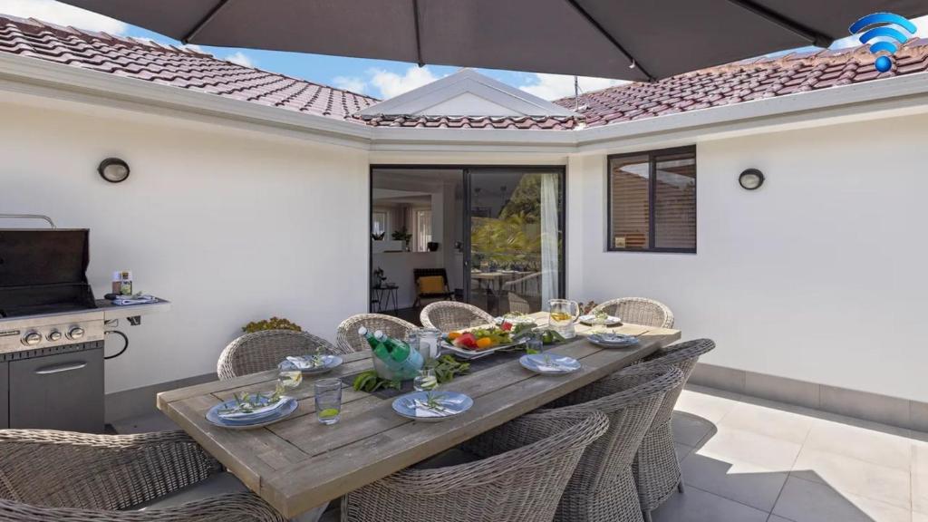 een houten tafel met stoelen en een maaltijd erop bij Baie de Salamandre in Salamander Bay