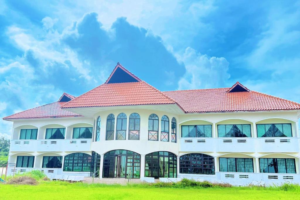 a large white building with a red roof at Met Blue Ocean Resort in Mersing