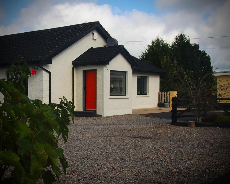 a small white house with a red door at Quiet Riverside Stopover by the Shannon in Leitrim