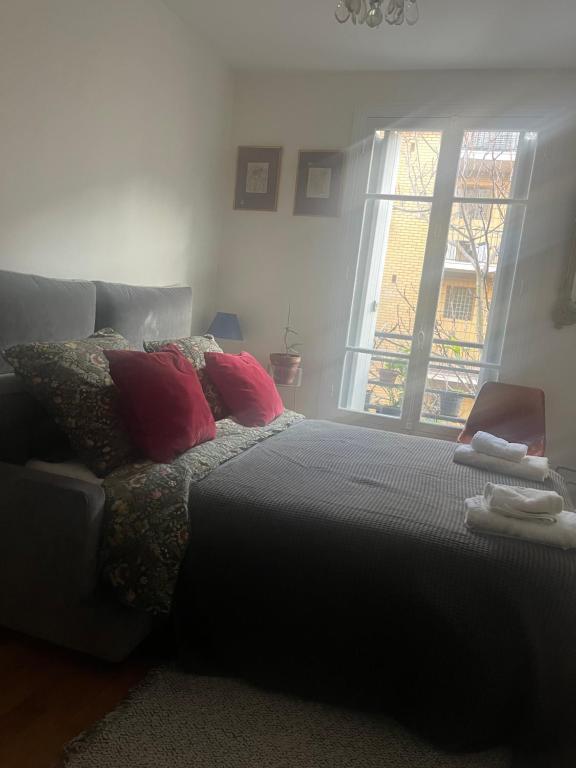 een slaapkamer met een bed met kussens en een raam bij Bedroom in Paris in Parijs