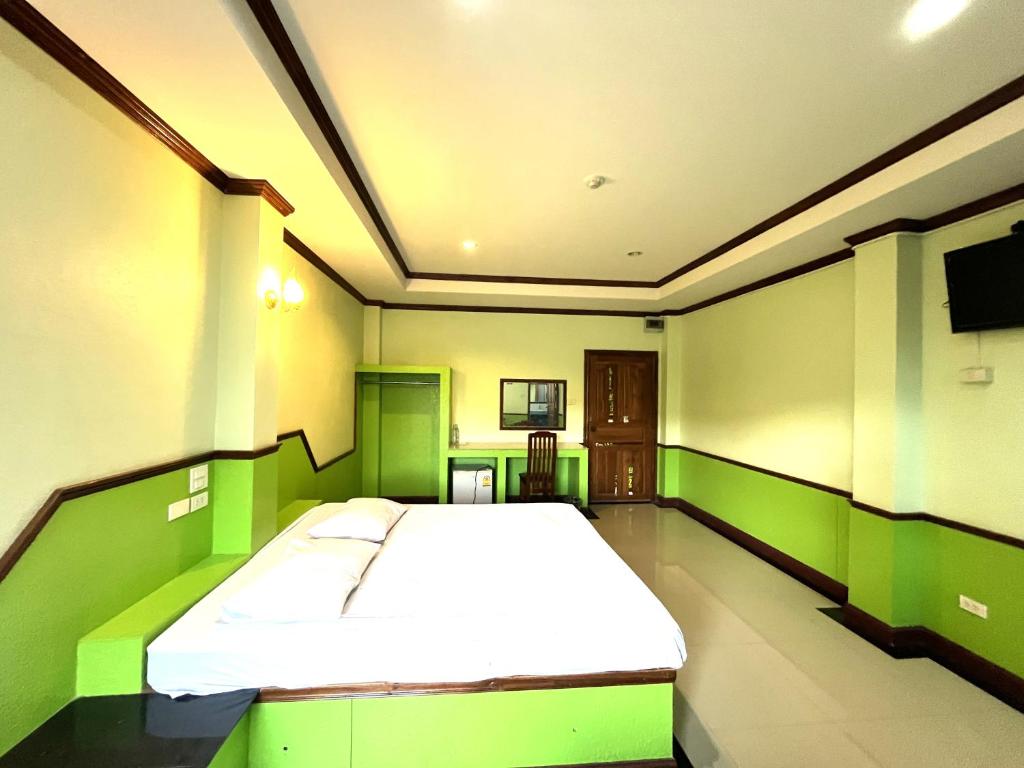 een slaapkamer met een groot bed met groene muren bij Godkan Hotel in Ban Chuk Kum