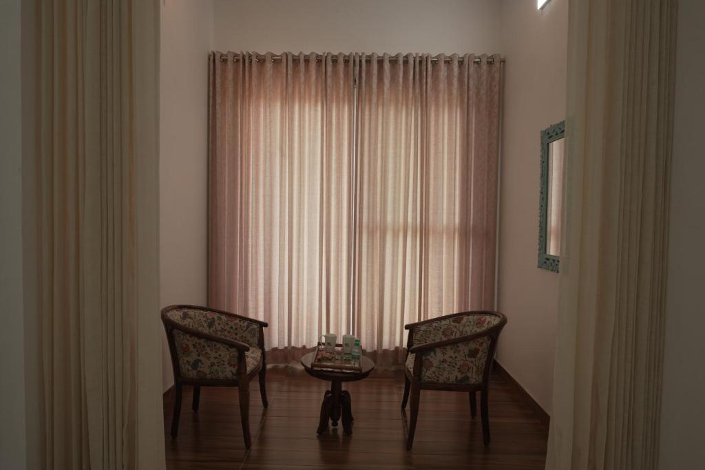 a room with two chairs and a table and a window at Jagir villa in Udaipur