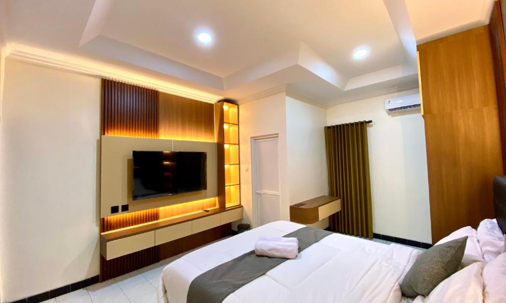 a hotel room with a bed and a flat screen tv at Kalandra Living in Yogyakarta