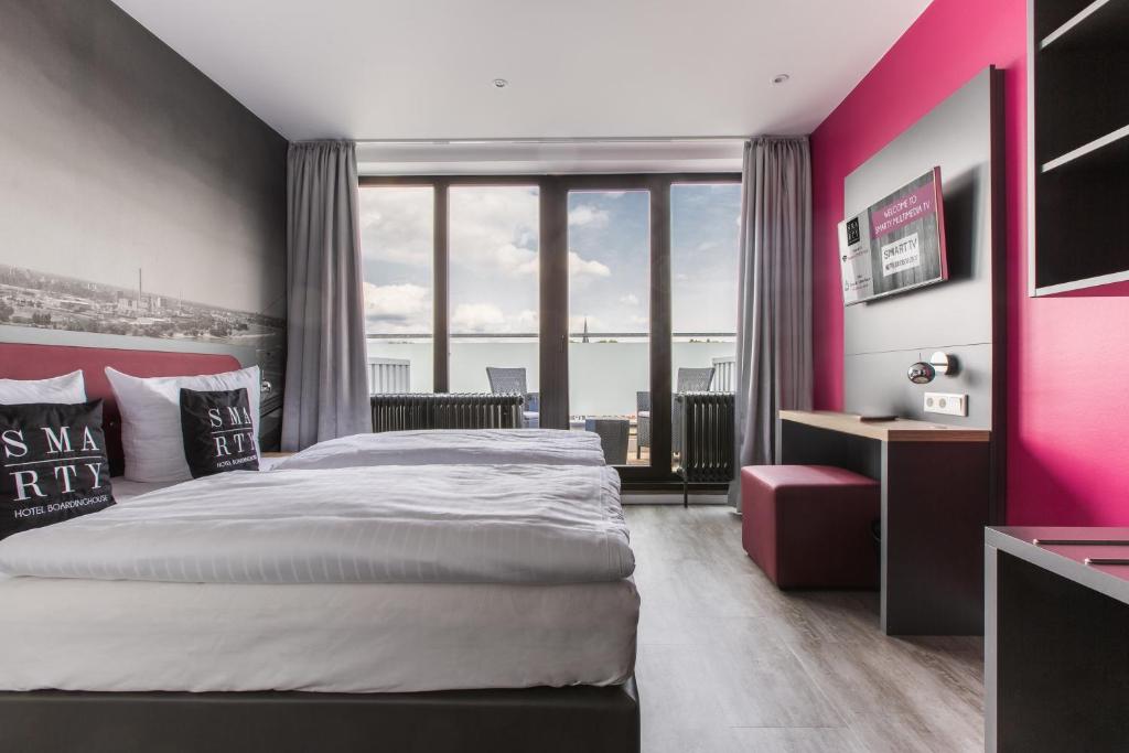 a bedroom with a large bed and a pink wall at SMARTY Leichlingen-Cologne - KONTAKTLOSER SELF CHECK-IN in Leichlingen