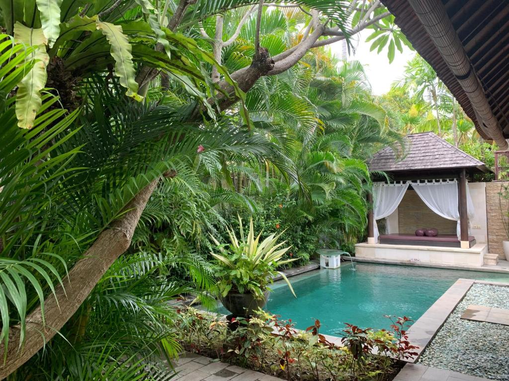 een zwembad in een tuin met palmbomen bij Nike Villas in Sanur