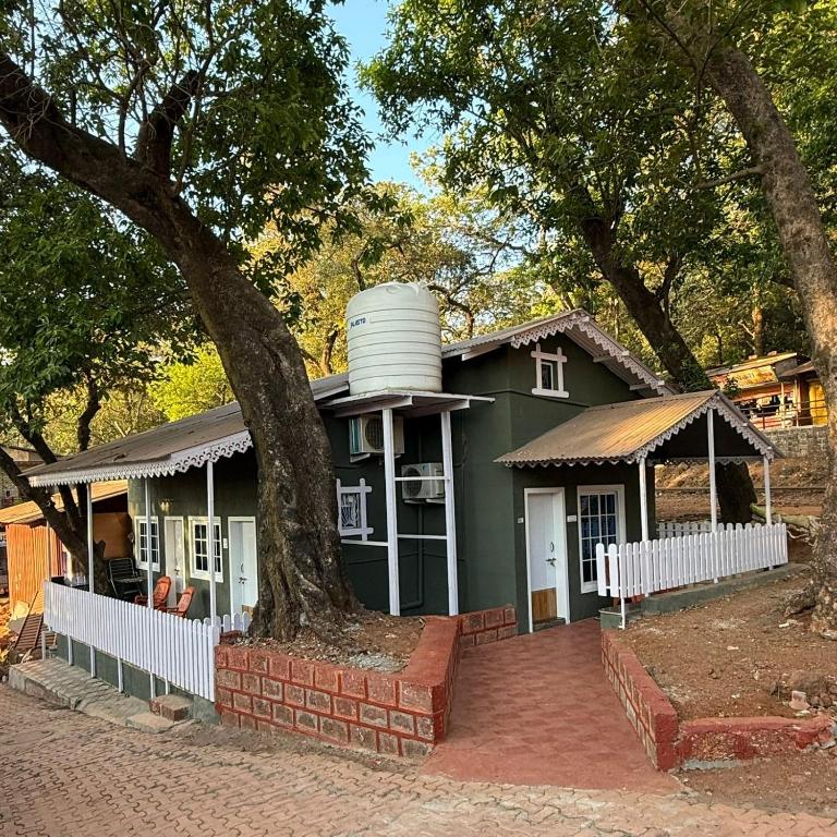 a green house with a water tank on top of it at Magic holiday home in Matheran