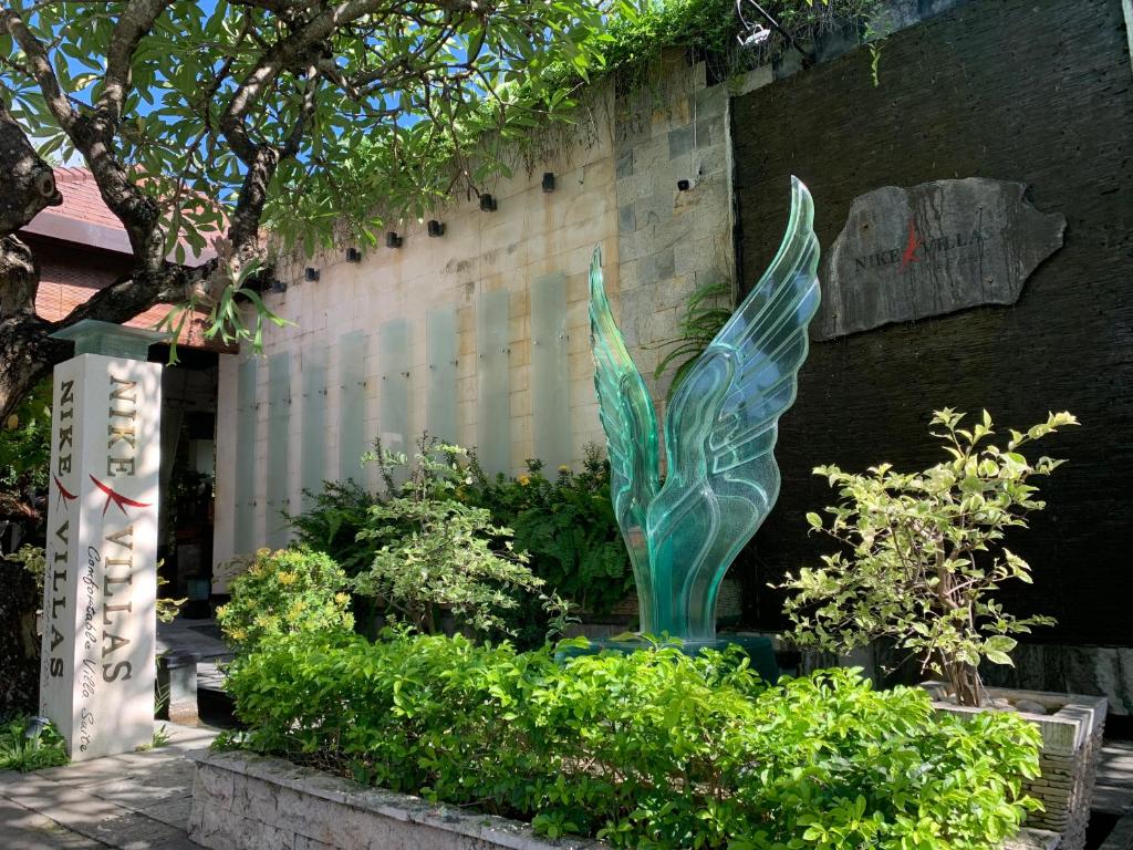 een groen beeld in een tuin naast een gebouw bij Nike Villas in Sanur
