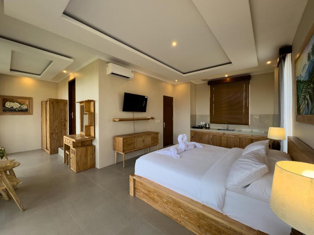 a bedroom with a white bed and a television at Koeluma Bali in Ubud
