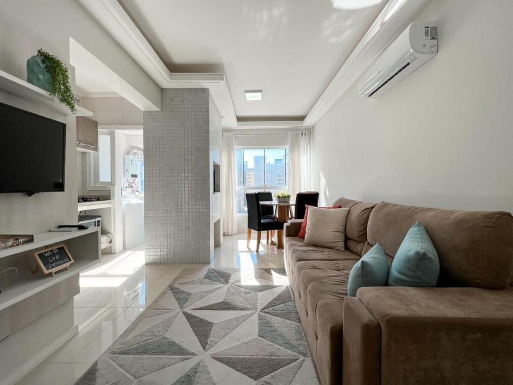 ein Wohnzimmer mit Sofa und Tisch in der Unterkunft Apartmento próximo ao mar in Capão da Canoa