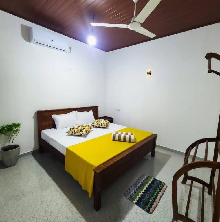 a bedroom with a bed with a yellow blanket on it at Meadow view unawatuna in Galle