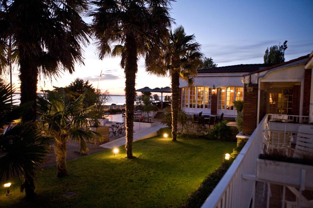 a house with a yard with palm trees and lights at Hotel et Spa Les Cleunes Oléron in Saint-Trojan-les-Bains