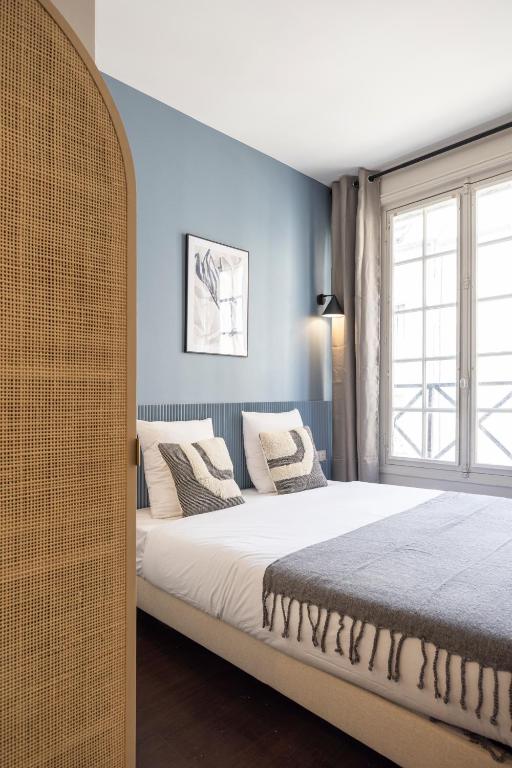 a bedroom with a bed with white sheets and a window at Air-conditioned and cozy haven in Le Pré-Saint-Gervais